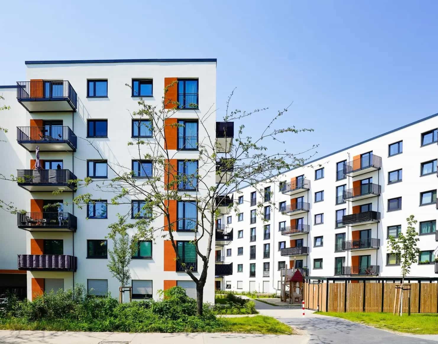 Mehrstöckiges modernes Wohngebäude mit Balkonen, umgeben von Grünflächen.